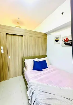 a bedroom with a large bed with blue pillows at Cozy Retreat at Shore2 Residences in Manila