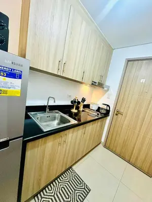 a kitchen with wooden cabinets and a sink and a refrigerator at Cozy Retreat at Shore2 Residences in Manila