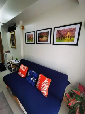 a blue couch in a living room with pillows on it at Aldo shore 3 tower 2 mall of Asia in Manila