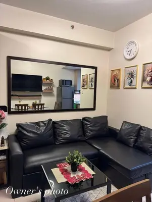 a living room with a black leather couch and a mirror at JUVREY 1 BR Studio Unit with balcony in Manila