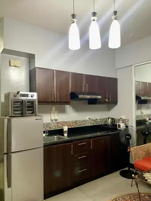 a kitchen with wooden cabinets and a stainless steel refrigerator at Tropical unit in Manila
