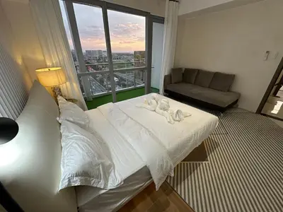 a bedroom with a bed and a couch and a window at Spacious 2BR Apartment Hotel near City of Dreams, Airport, MOA, Okada, Ayala Malls, and Solaire Casino with free 5 pool access in Manila