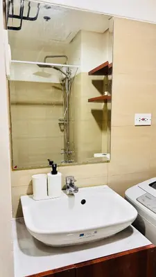 a bathroom with a white sink and a mirror at GreySky Studio in Manila