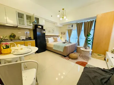 a room with a bed and a table and a kitchen at Cozy Studio in Viceroy Near Venice Mall in Manila