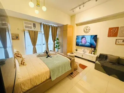 a bedroom with a bed and a flat screen tv at Cozy Studio in Viceroy Near Venice Mall in Manila