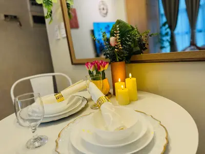 a table with white plates and candles and flowers at Cozy Studio in Viceroy Near Venice Mall in Manila