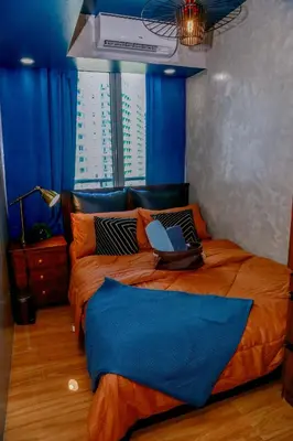 a bedroom with a bed with orange sheets and blue walls at Azure Urban Resort Staycation 2 bedrooms beach view, 9th floor in Manila