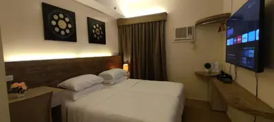 a hotel room with a bed and a flat screen tv at Cozy Suite with Private Patio near Nuvali in Silang