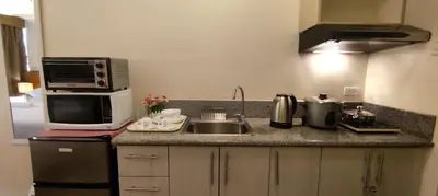 a kitchen with a sink and a microwave at Cozy Suite with Private Patio near Nuvali in Silang