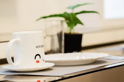 a white coffee cup sitting on a table with a plate at Family Suite near MOA in Manila