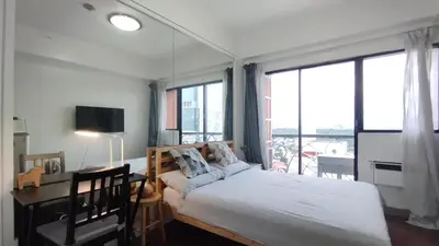 a bedroom with a bed and a desk and windows at Delet CITADEL in Manila