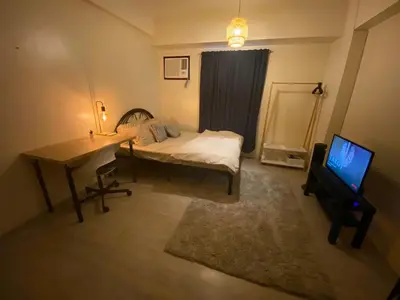 a bedroom with a bed and a desk and a television at The Mood Shift in Manila