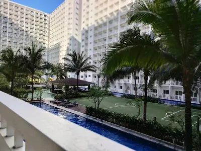 a tennis court on the balcony of a hotel with palm trees at Shore Residences - 2 Bedroom Pool View Near Moa in Manila