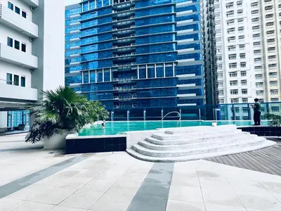 a large building with a pool in front of it at Crisean Highrise Condo - 100 West makati in Manila