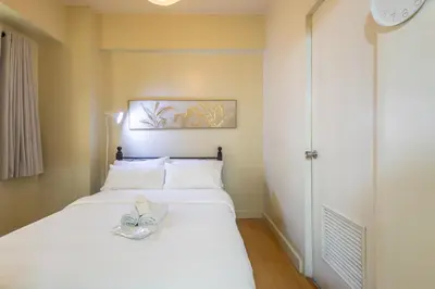 a bedroom with a bed with a pair of shoes on it at Forbeswood Heights 1Br with Garden view in Manila