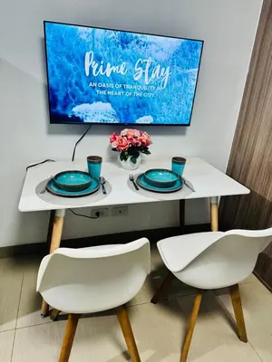 a white table with two chairs and a tv on a wall at 726 Shore 2 Residences near SM MOA & IKEA by Prime Stay in Manila