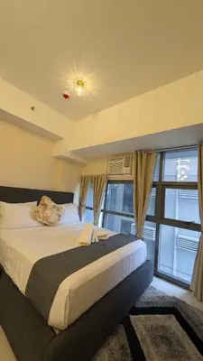 a bedroom with a large bed and a large window at J&M Cozy Retreat - McKinley Hill, BGC in Manila