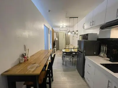 a kitchen with a wooden table and a dining room at AA Cozy Comfort in Nuvali in Calamba