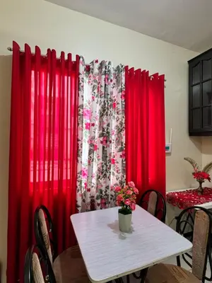 a dining room with red curtains and a table with flowers at Las Asturias in Balibago