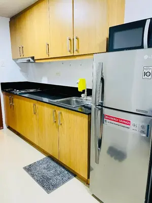 a kitchen with a stainless steel refrigerator and wooden cabinets at Shell Residences Condotel by Aiza in Manila