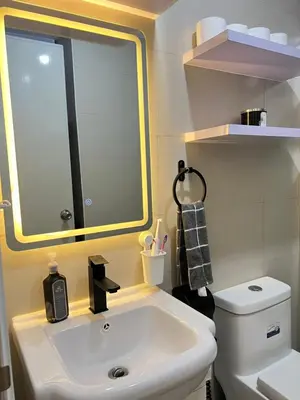 a bathroom with a sink and a mirror and a toilet at Aesthetic 2BR Penthouse near NAIA with Pool in Manila