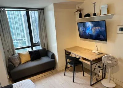 a living room with a desk and a couch and a table at Studio in Greenbelt with Wifi, Pool and Gym in Manila
