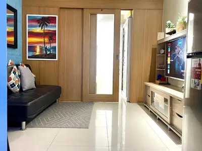 a living room with a black couch and a television at MOA Shell Residences - Big Balcony Facing Pool in Manila
