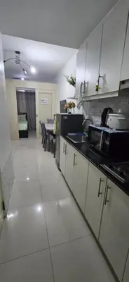 a kitchen with white cabinets and a table in it at Jhang places sea residence in Manila