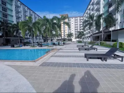 a pool with benches and palm trees and buildings at Field Residences King Elite Near NAIA Arport in Manila