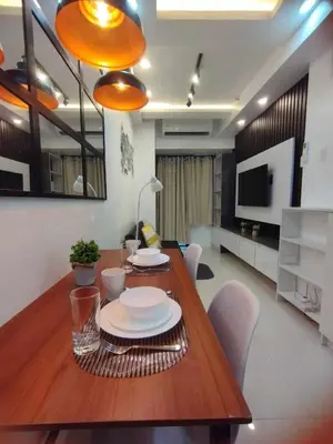 a dining room with a wooden table with plates on it at Stylish Getaway in the Heart of the City - Mall of Asia in Manila