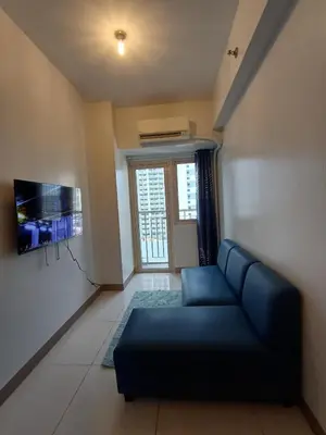 a living room with a blue couch and a tv at Cozy and Comfortable 1BedRoom at Coast Residences in Manila