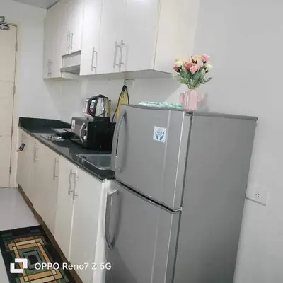 a kitchen with a refrigerator with a vase of flowers on it at Kim Place at Sea Residences near Moa in Manila