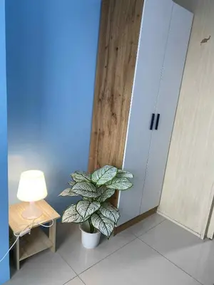 a plant in a room next to a table and a lamp at Kim Place at Sea Residences near Moa in Manila