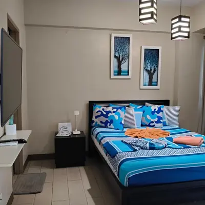 a bedroom with a bed with blue and white sheets at LDN Secret Crib -Two palm tree across NAIA Terminal 3 in Manila