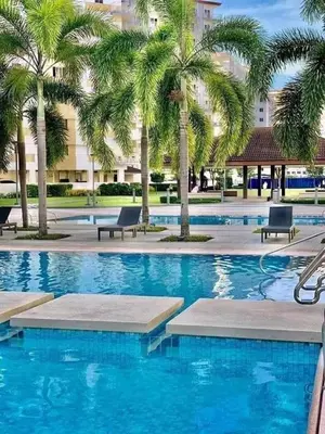 a swimming pool with palm trees in a hotel at 2BR Family suite with Balcony with WiFi and Netflix, behind SM Sucat in Manila