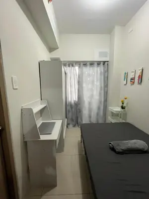 a small white room with a bed and a desk at 2BR Family suite with Balcony with WiFi and Netflix, behind SM Sucat in Manila