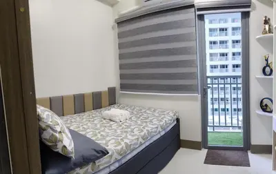 a small bedroom with a bed and a window at fame residence staycation in Manila