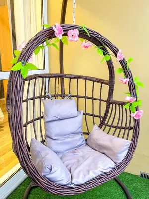 a wicker swing chair with pink flowers and pillows at Bayshore 9g 4br in Manila