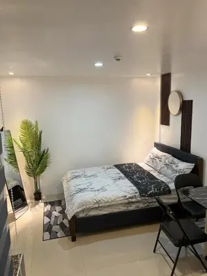 a bedroom with a bed and a table and a plant at Cozy Studio near MOA, Airport & Star City, Pasay in Manila