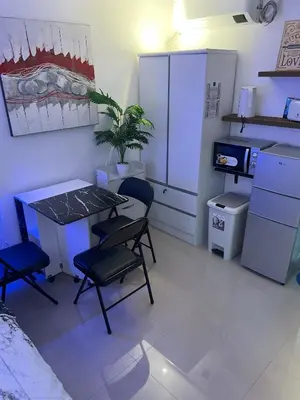 a kitchen with a table and chairs and a refrigerator at Cozy Studio near MOA, Airport & Star City, Pasay in Manila