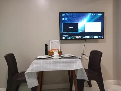a table with two chairs and a tv on the wall at Condotel nearby MOA with Pool Access in Manila
