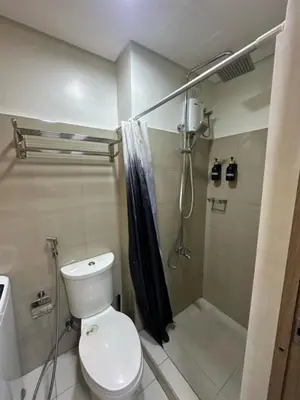 a bathroom with a toilet and a shower with a shower curtain at Shore 2 Residence Homes Near MOA in Manila