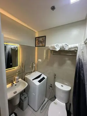 a bathroom with a white toilet and a sink at Shore 2 Residence Homes Near MOA in Manila