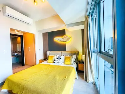 a bedroom with a large bed with yellow sheets at Luxury 2BR Penthouse Across Uptown BGC I Modern in Manila