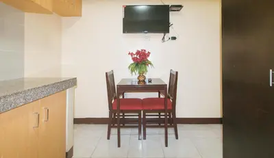 a dining room table with a vase of flowers on it at J and T Jamich Suites by RedDoorz in Manila