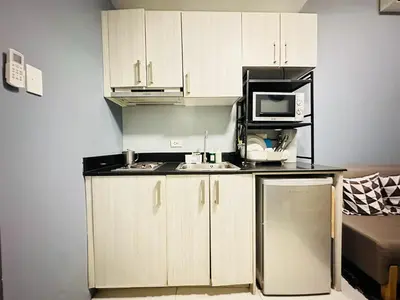 a kitchen with white cabinets and a microwave oven at STYLISH LUXE APARTMENT in SMDC GREEN RESIDENCES in Manila