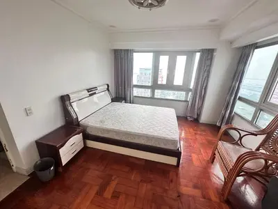 a bedroom with a bed and a chair and windows at Tranquil Harbor in Manila