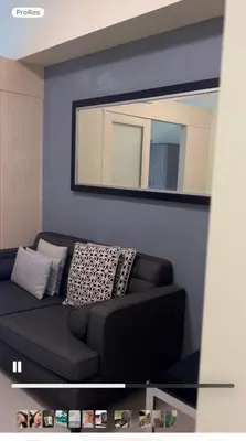 a living room with a black couch and a mirror at Jazz Residences Tower B Makati in Manila