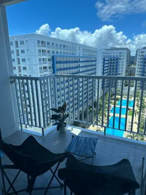 a balcony with chairs and a view of a city at Sea Residences 2BR Pool View Unit for 4-8 pax - Beehive Stay MOA in Manila