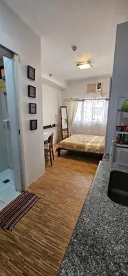 a bedroom with a bed and a desk in a room at Laidback Cavern at Studio City Alabang in Manila